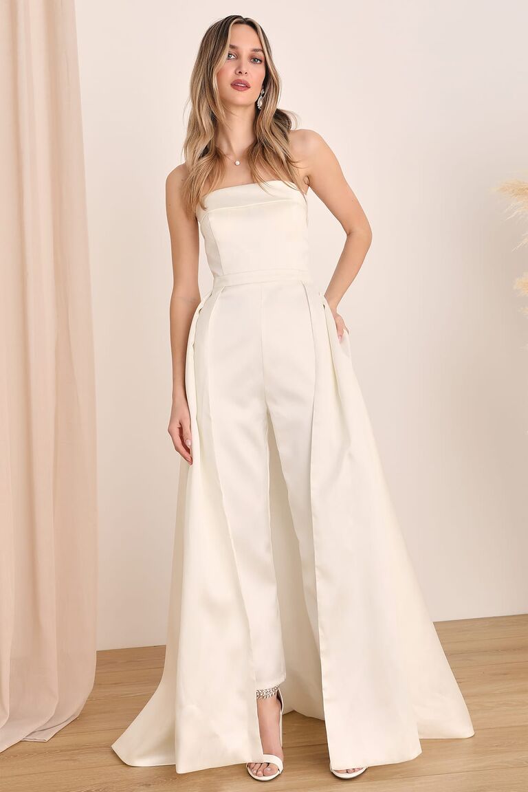 Model wears a white jumpsuit with detachable skirt. 