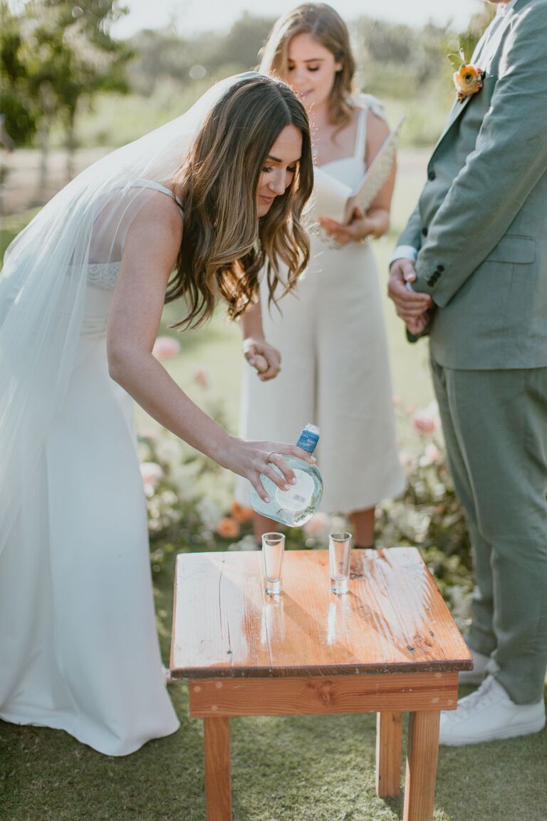 Bride pouring tequila shot during ceremony