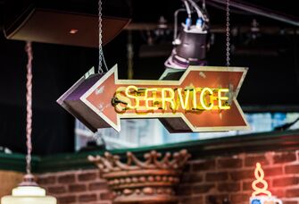 Orange hanging arrow sign that reads 'Service' in neon yellow