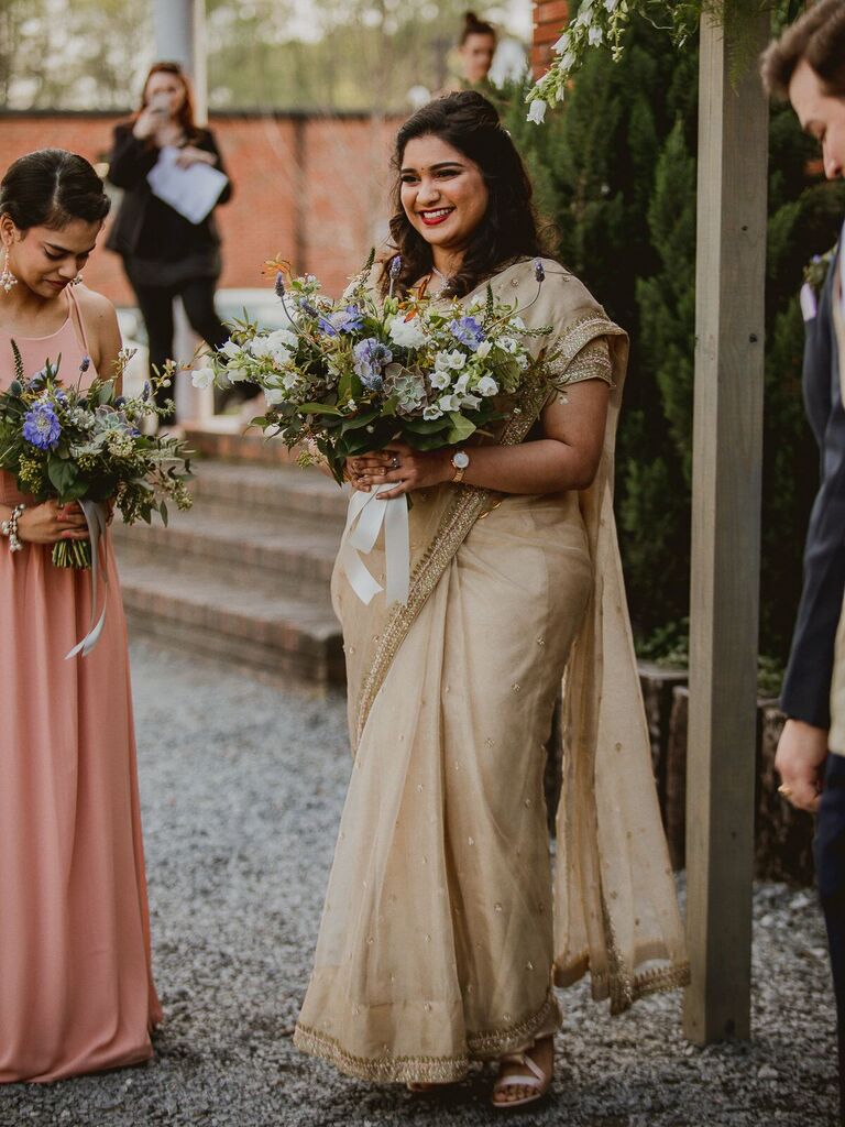 Smiling bride wearing a cream Indian wedding sari.