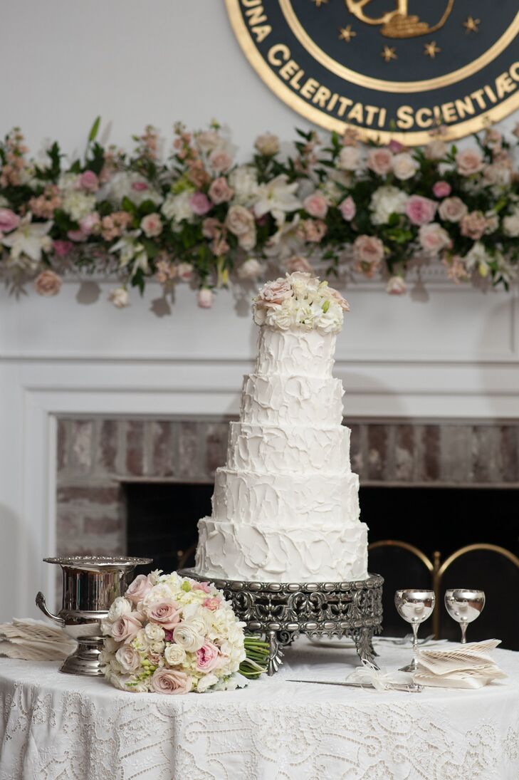 The couple's five-tiered round cake was unevenly frosted for a rustic look and topped with a romantic bouquet of flowers.