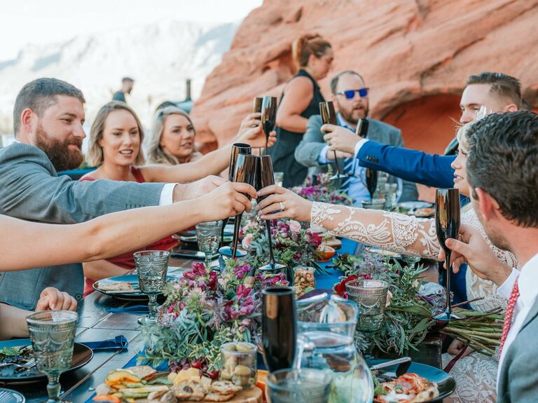 Wedding party toasts to the newlyweds at an outdoor bohemian celebration. 
