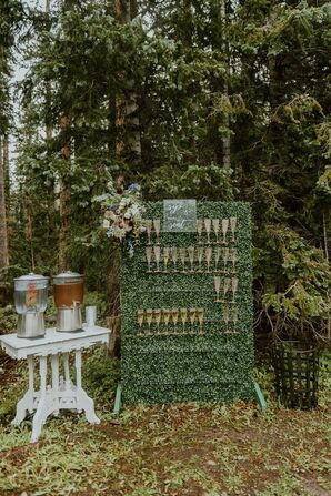 Greenery Wall With Champagne Flutes as Escort Cards at a Rustic Outdoor Wedding