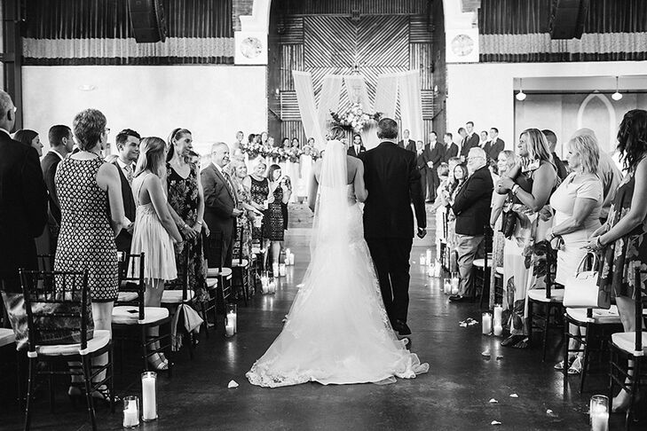 Candles of various sizes were placed at the end of each row to line the aisle during the ceremony. The couple had a 15-foot cross built for the stage and hung fresh flowers and draping greenery from it to complete the romantic look.