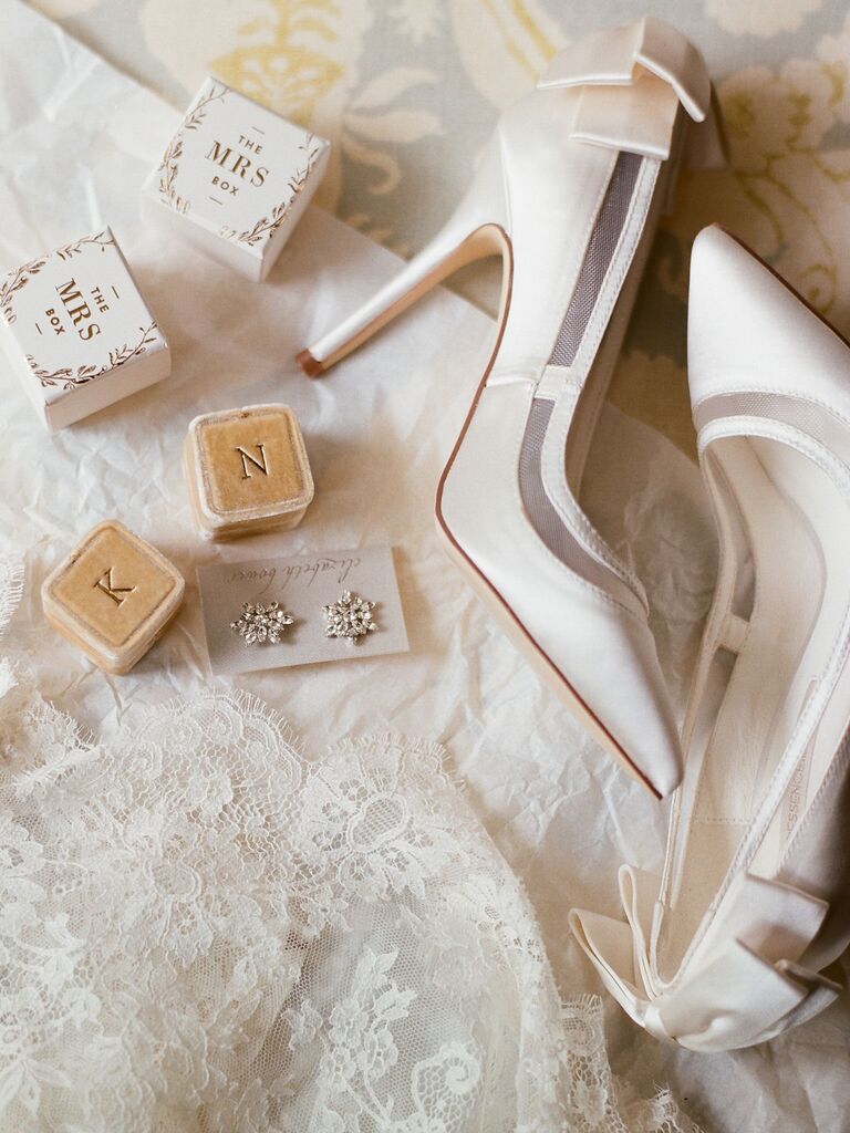 Ivory satin wedding high heels with gold velvet ring boxes on white lace backdrop