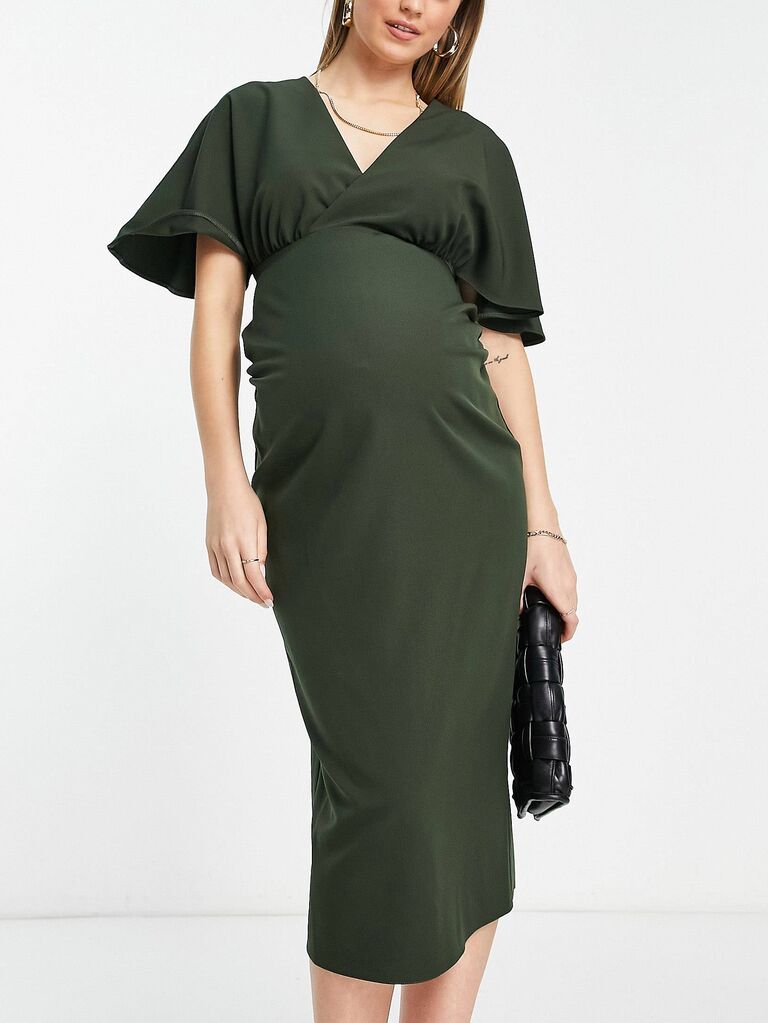 Model wears forest green dress with a V-neckline and fluttering sleeves. 