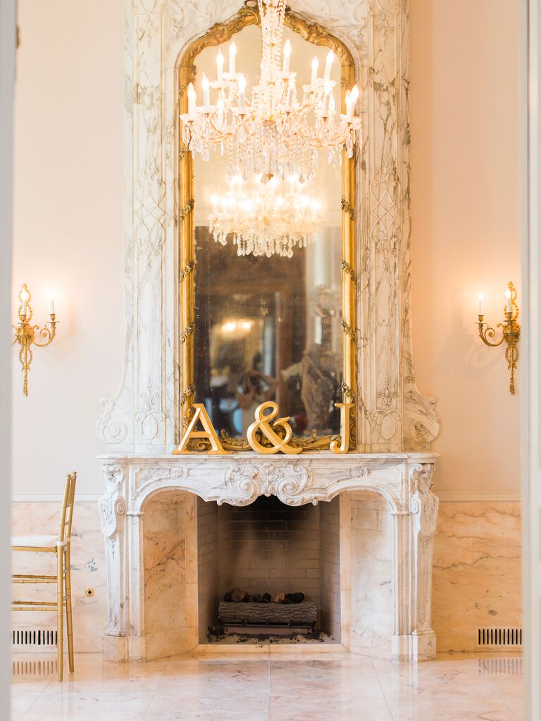ornate marble wedding fireplace decorated with gold mirror and gold initial letters