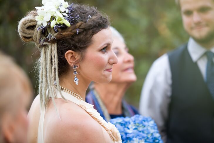 Aly wore her dreadlocks in a braided updo on the wedding day, and her hairdresser accented her hair with white stephanotis flowers that complemented her cream-colored bohemian dress.