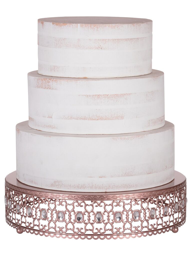 Ornate rose gold and crystal wedding cake stand holding three-tier cake