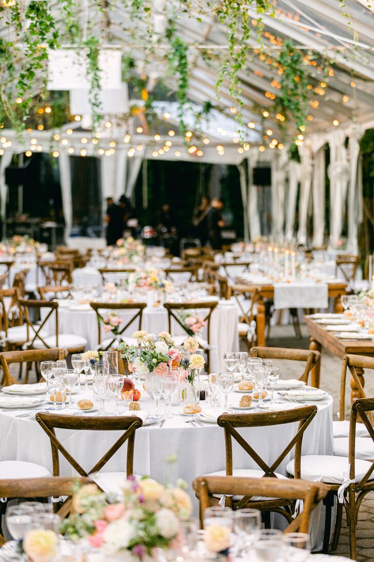 Round Tables With White Linens and Pastel Centerpieces Under Hanging Flowers