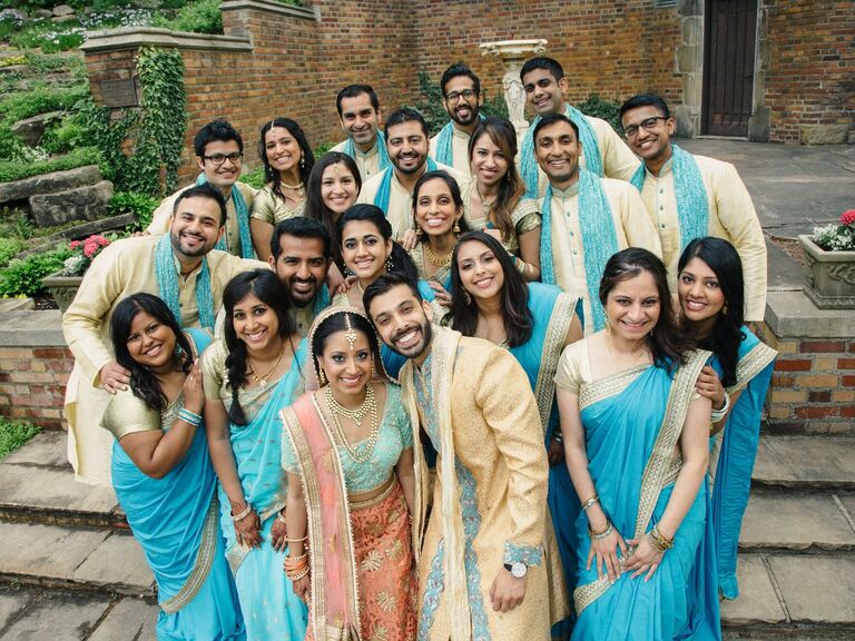 Wedding party photo with bridesmaids wearing gold and turquoise sarees.