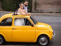 Couple standing thru sunroof of car