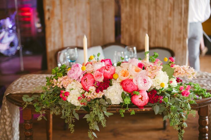 Lauren and Brian always loved to sit on the same side of the table, and so they did at their sweetheart table, which had them facing all their seated guests. The table had a colorful centerpiece draped over the front, filled with hydrangeas, peonies and roses—not to mention the tall white candlesticks that created a romantic touch.