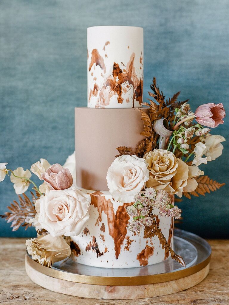 rustic fall wedding cake with painted cowhide-inspired design and pastel blush roses with dried grass