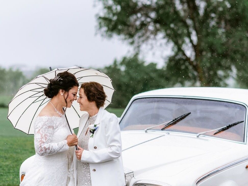 A couple lean close beneath a white parasol.