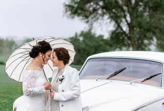 A couple lean close beneath a white parasol.