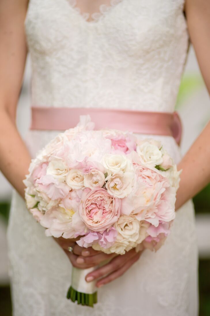 Inspired by her  grandmother's garden, Nellie chose peonies for the day's main flower. She carried a classic bouquet of f white and pink peonies with coral garden roses and ranunculus, tied with an ivory satin ribbon and pearl pins.