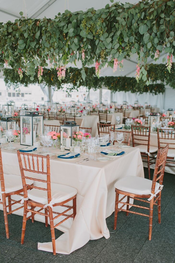 The white wedding tent was decorated with hanging eucalyptus. Reception tables had lantern and small votive centerpieces with coral-toned flowers and eucalyptus.