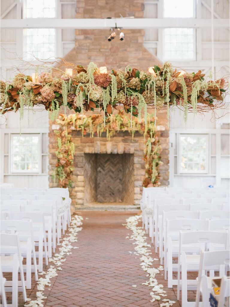 indoor wedding ceremony with hanging flower centerpiece and matching wedding fireplace decor