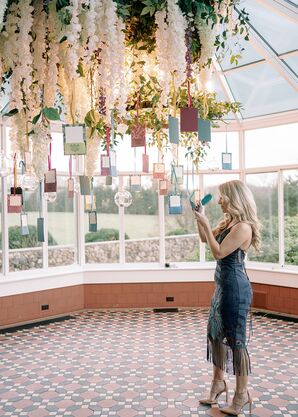 Guest Writing Well Wishes on Hanging Cards on Wishing Tree at Royal-Inspired Reception