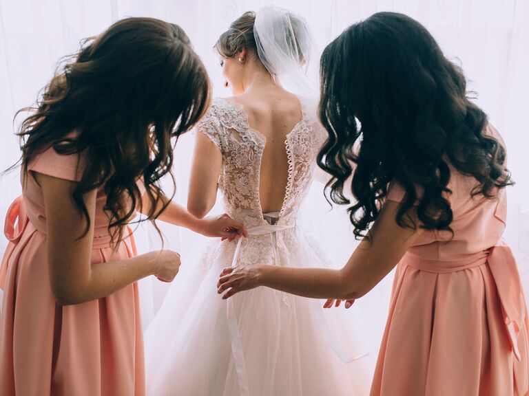 bridemaids helping the bride get into wedding dress
