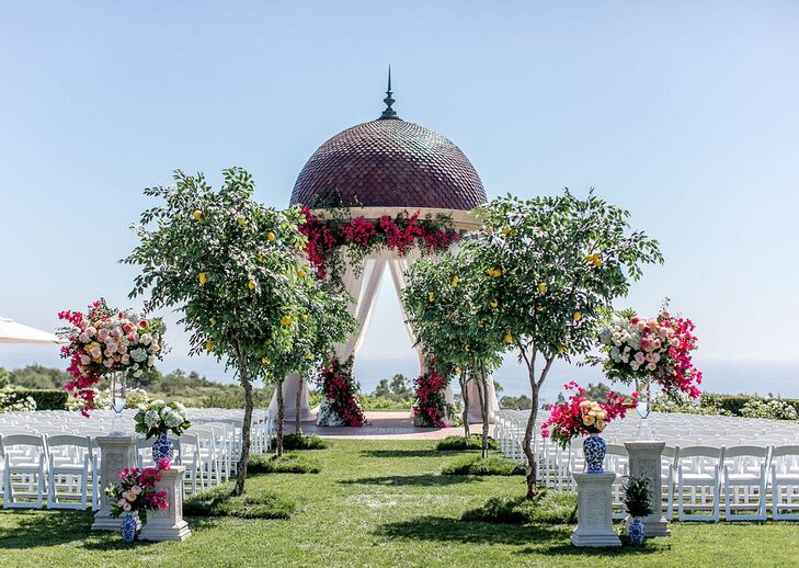 Luxurious Waterfront Ceremony Site with Trees, Colorful Flowers and Folding Chairs