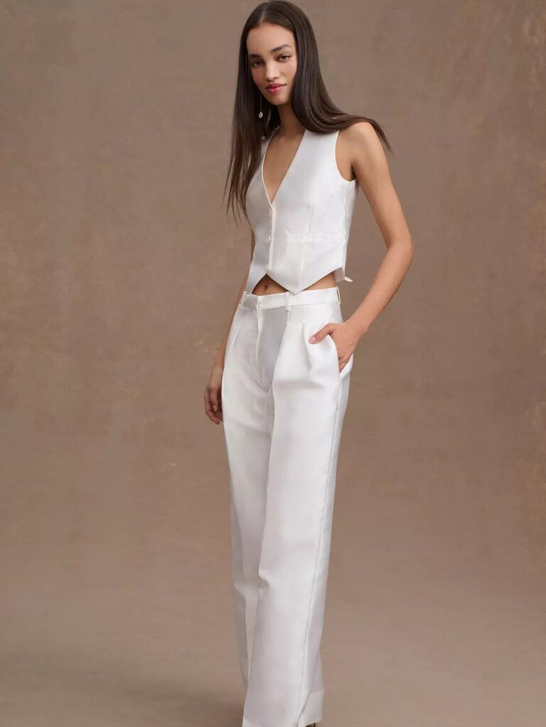 Model wears wear trousers and a matching button-up vest. 