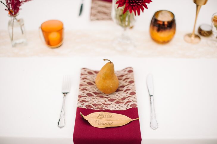 Even the escort cards felt like fall. Shelby made one for every guest by spray-painting magnolia leaves gold and then writing every guest's name. They were placed near Bosc pear wedding favors.