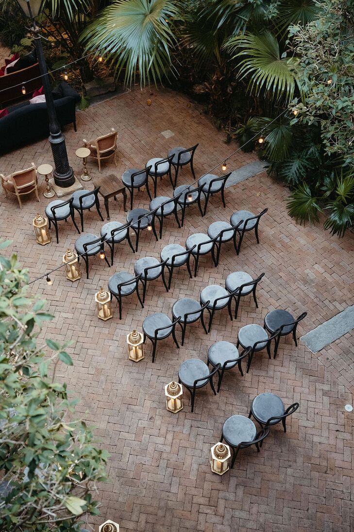 Black Chairs in Courtyard, Gold Lanterns Lining Aisle, Trees and String Lights
