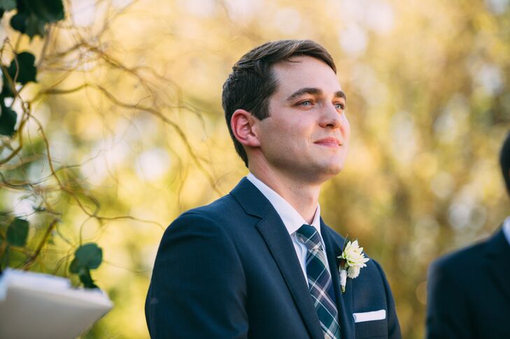 Ryan wore a navy suit with a plaid tie on his wedding day. He also wore a white boutonniere with chrysanthemum, dahlia and his favorite herb, rosemary.
