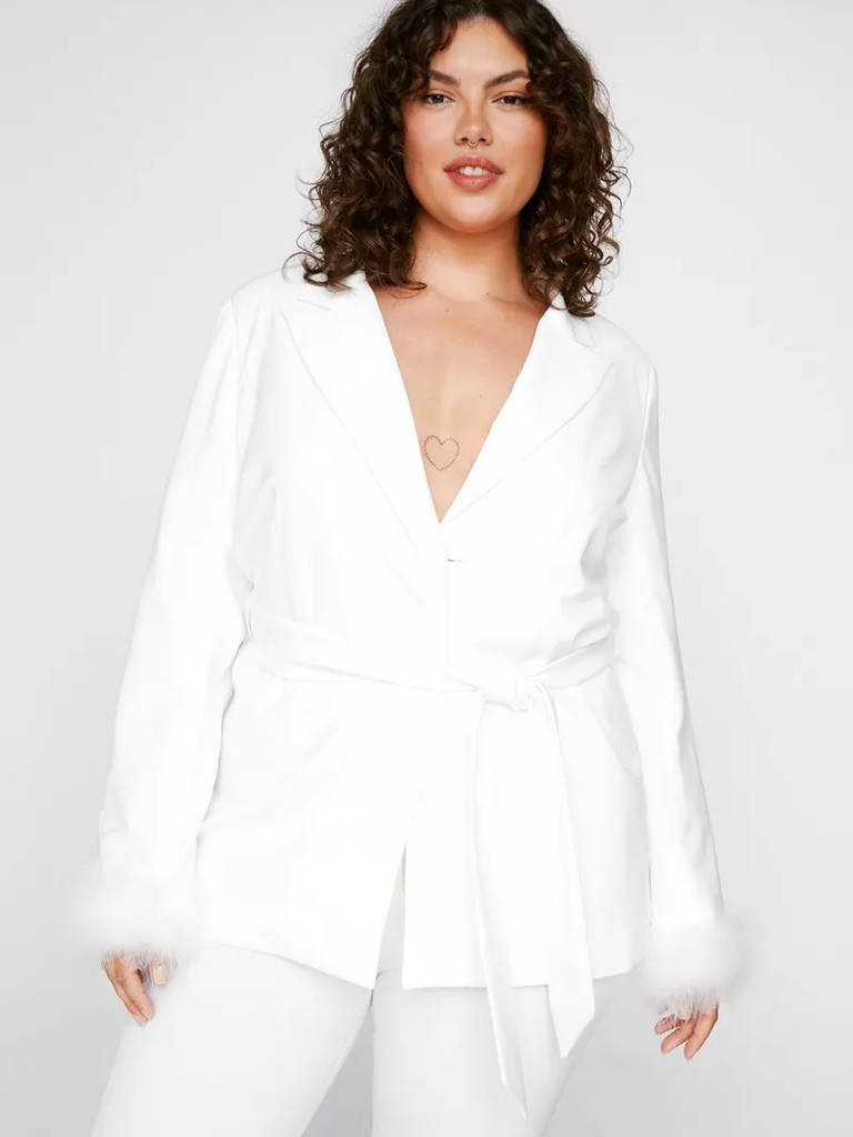 A model shows off this blazer-style white jumpsuit with feather cuffs.