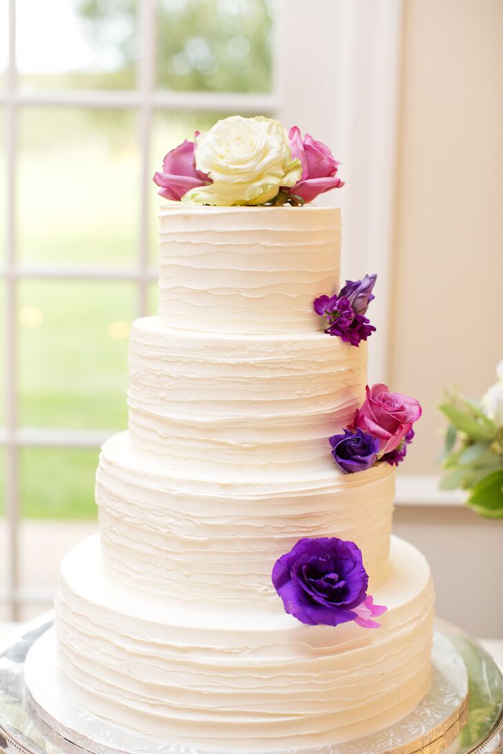 A four-tiered cake frosted in vanilla cream and adorned with purple flowers was simply elegant.