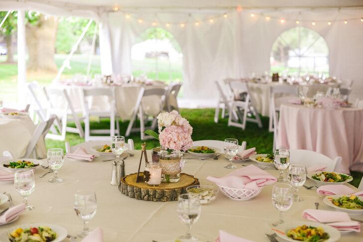 At the tented reception, tables were dressed in ivory and pink linens with a centerpiece on a slab of wood. The centerpieces were made up of mason jars filled with hydrangeas.