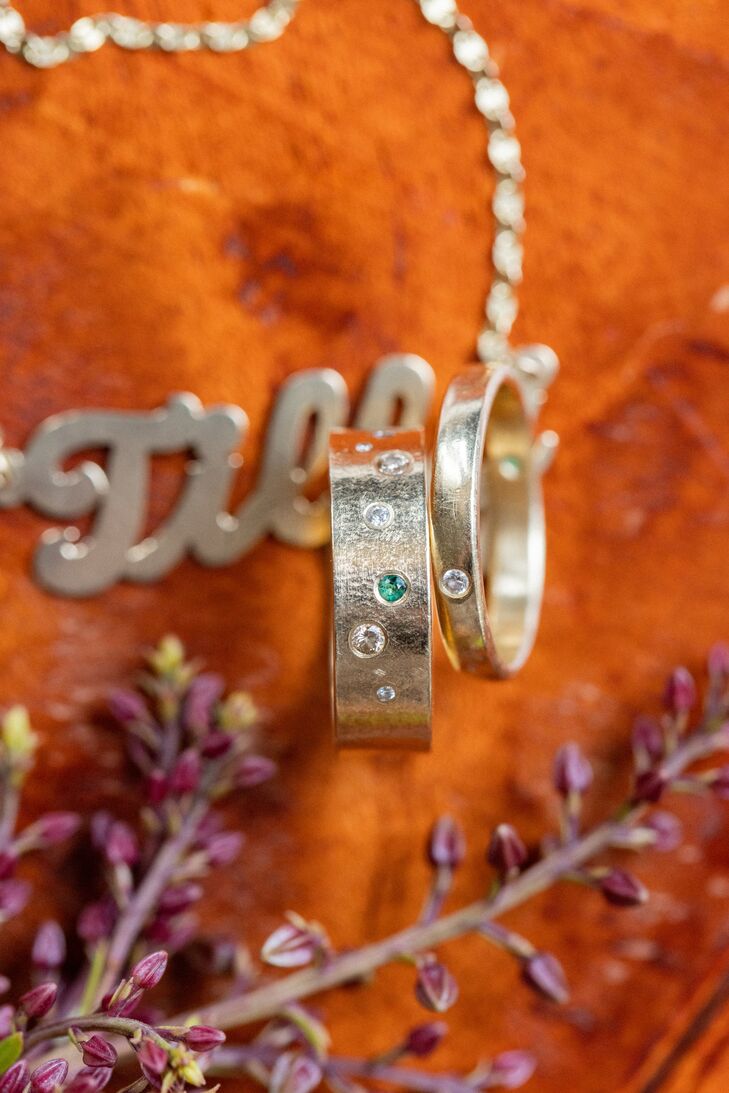 Two Gold Wedding Bands With Small Diamonds and Green Gem Embedded