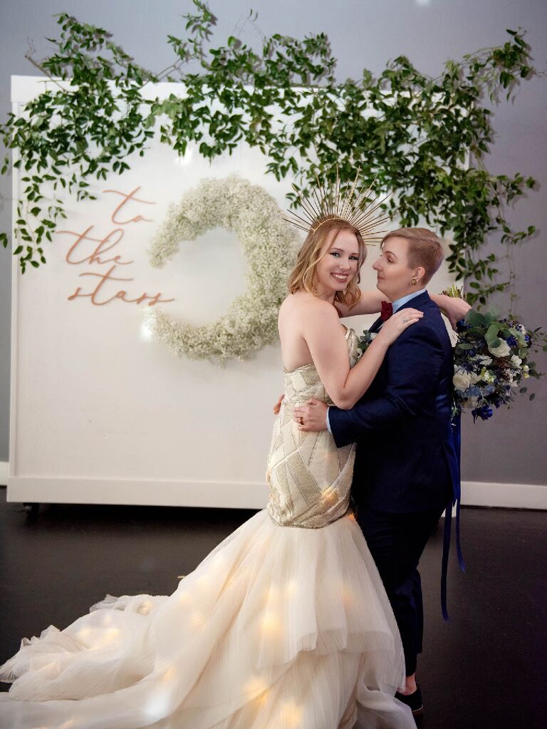 Couple posing in front of "To The Stars" celestial wedding sign