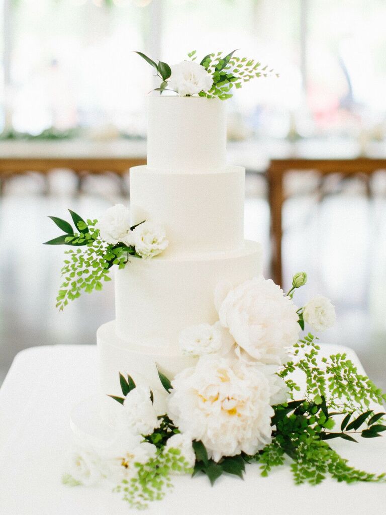 four tier white wedding cake with white peonies and greenery