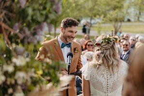 Groom in Orange Suit Holds the Mic During Ceremony With Bride in Lace Dress