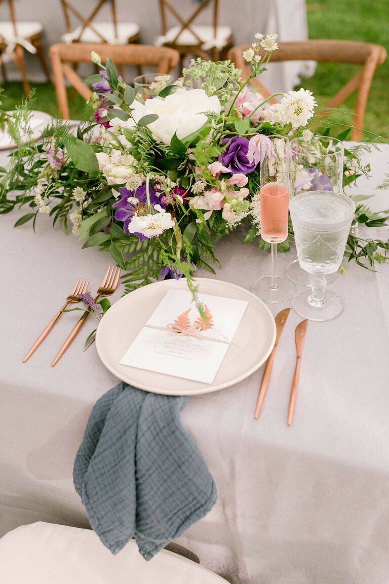 Romantic place setting with fern-centric centerpieces and blue napkins