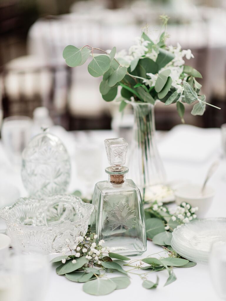 A delicate glass floral centerpiece with white flowers and greenery.