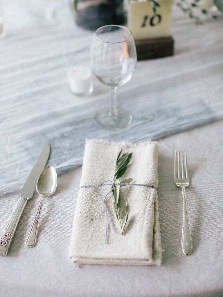 simple wedding table decor with ivory cloth napkin tied with thin string and greenery branch