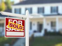 Sold "For Sale" sign in front of house