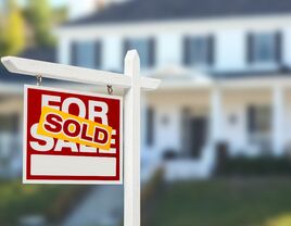 Sold "For Sale" sign in front of house