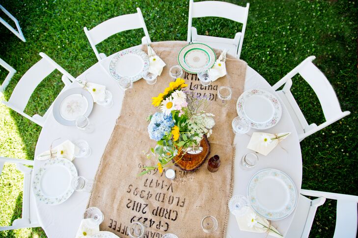 Tables were set with burlap table runners, mix-matched vintage plates and  local flower arrangements set atop handmade wood slabs.