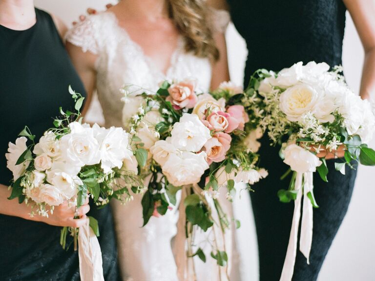 A bride and her bridesmaids hold white and pale pink bouquets.
