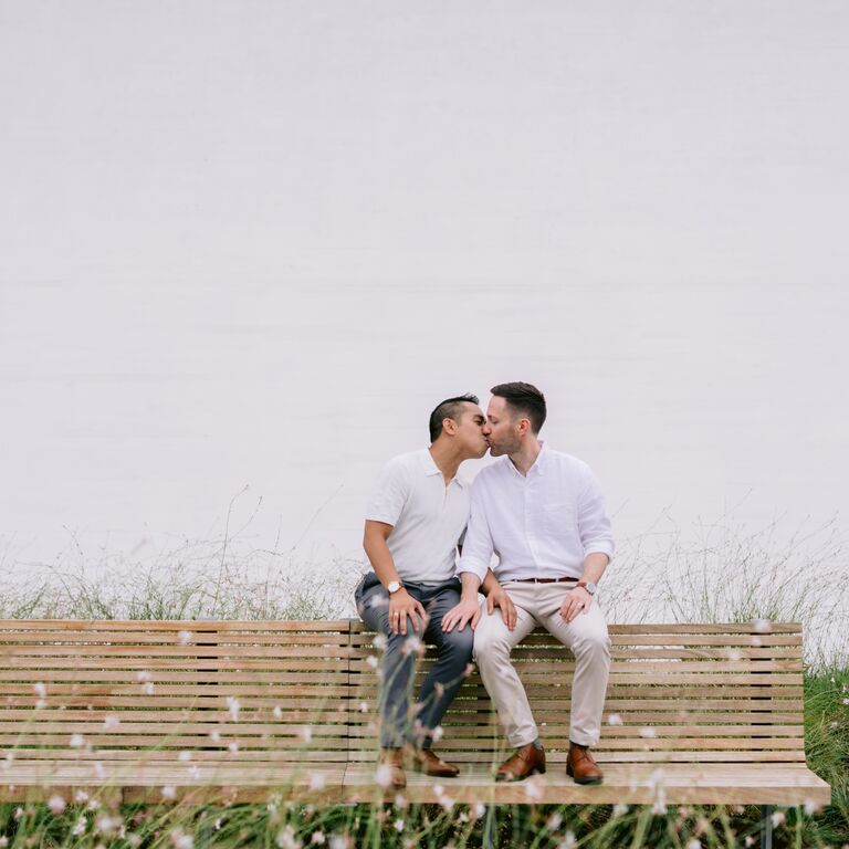 Beachside bench kissing engagement photo