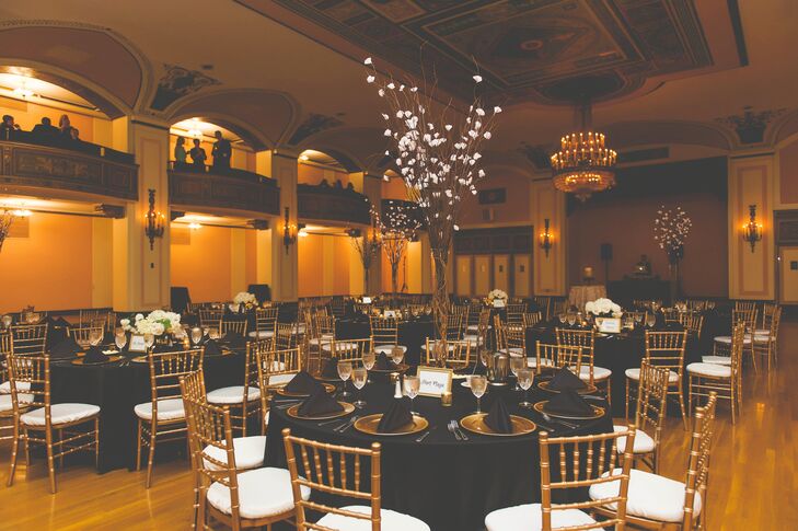 Gold chiavari chairs and dinnerware popped against all-black linens within the airy ballroom space. "Our color scheme fit our venue perfectly," Laurie says. "We loved the old charm of the venue and gold and black made everything seem so elegant."