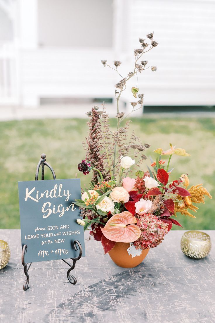 Calligraphed slate sign sitting beside floral arrangement