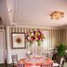 The couple's florist, Garden District-Naples, paired each floral linen with an overflowing centerpiece. Roses in fuchsia, orange and red were paired with bright spray roses, white and pink hydrangeas and greenery. Each arrangement either topped a clear-glass trumpet vase or a low pedestal vase. They also matched the couple’s table numbers.