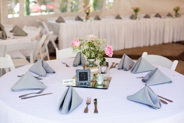 At the white tented reception at Lairmont Manor in Bellingham, Washington, dining tables dressed in white linens had pink rose and baby's breath centerpieces decorating the middle—arranged inside mason jars wrapped with lace that gave off a vintage vibe.
