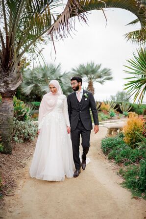 Bride Wearing Hijab Walking by Palm Trees With Groom in Gray Suit